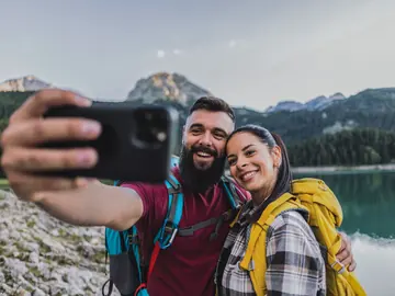 A hiking couple taking a selfie by a mountain lake