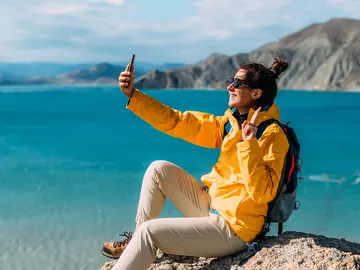 Traveler taking a selfie beside a turquoise mountain lake