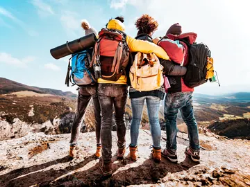 Four friends with backpacks on a mountain summit