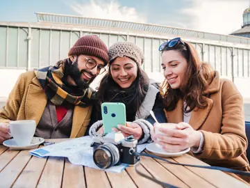 Friends planning a trip over coffee with a map and camera