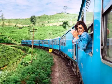 Traveler on a blue train through green hills
